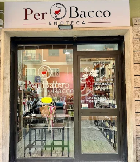 Ingresso dell'Enoteca Per Bacco con insegna bianca e porta a vetri con scritte Vini, Bollicine, Distillati, Liquori